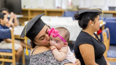 mother graduate kissing her baby